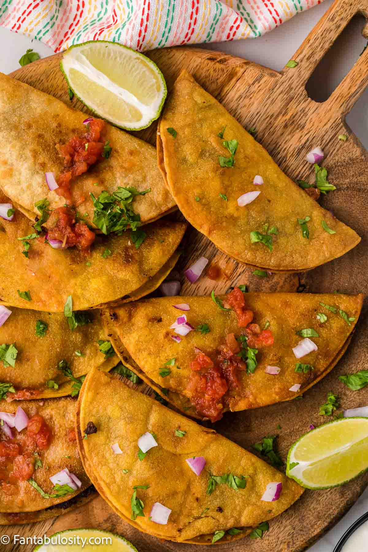 Cooked fried tacos on wooden cutting board.