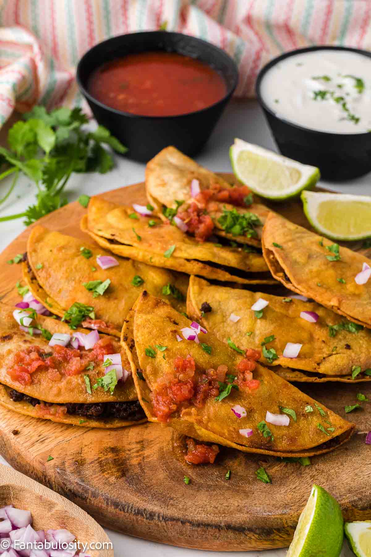 Fried tacos on a wooden cutting board.