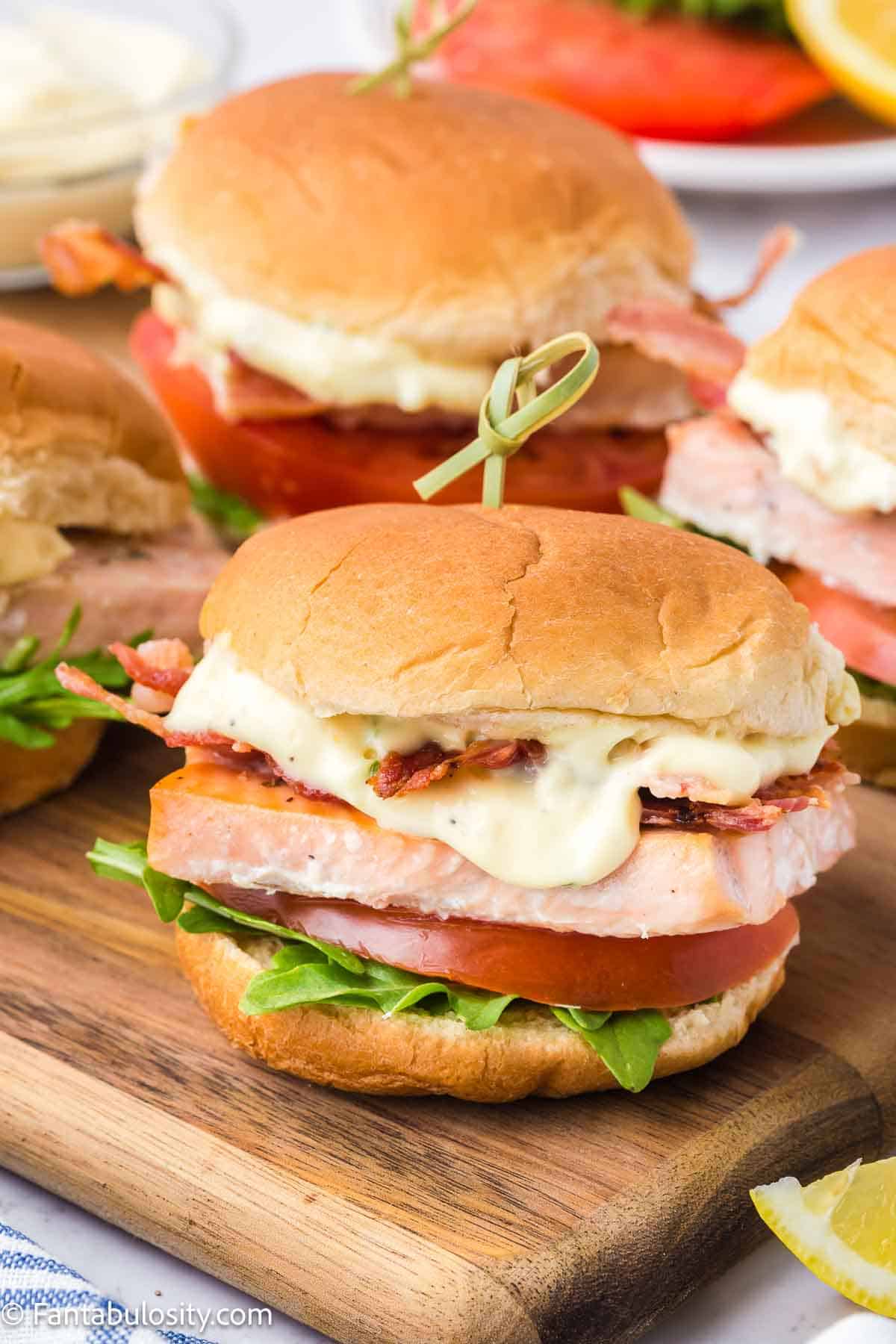 Salmon sliders on wooden cutting board.