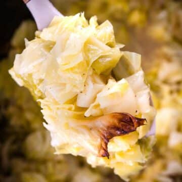 Close up of cooked cabbage from the slow cooker in a spoon.