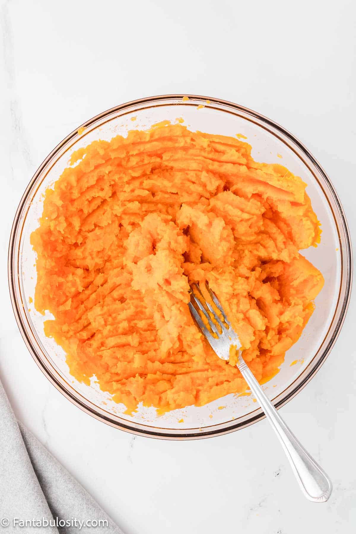 Mashed sweet potatoes in clear glass bowl.