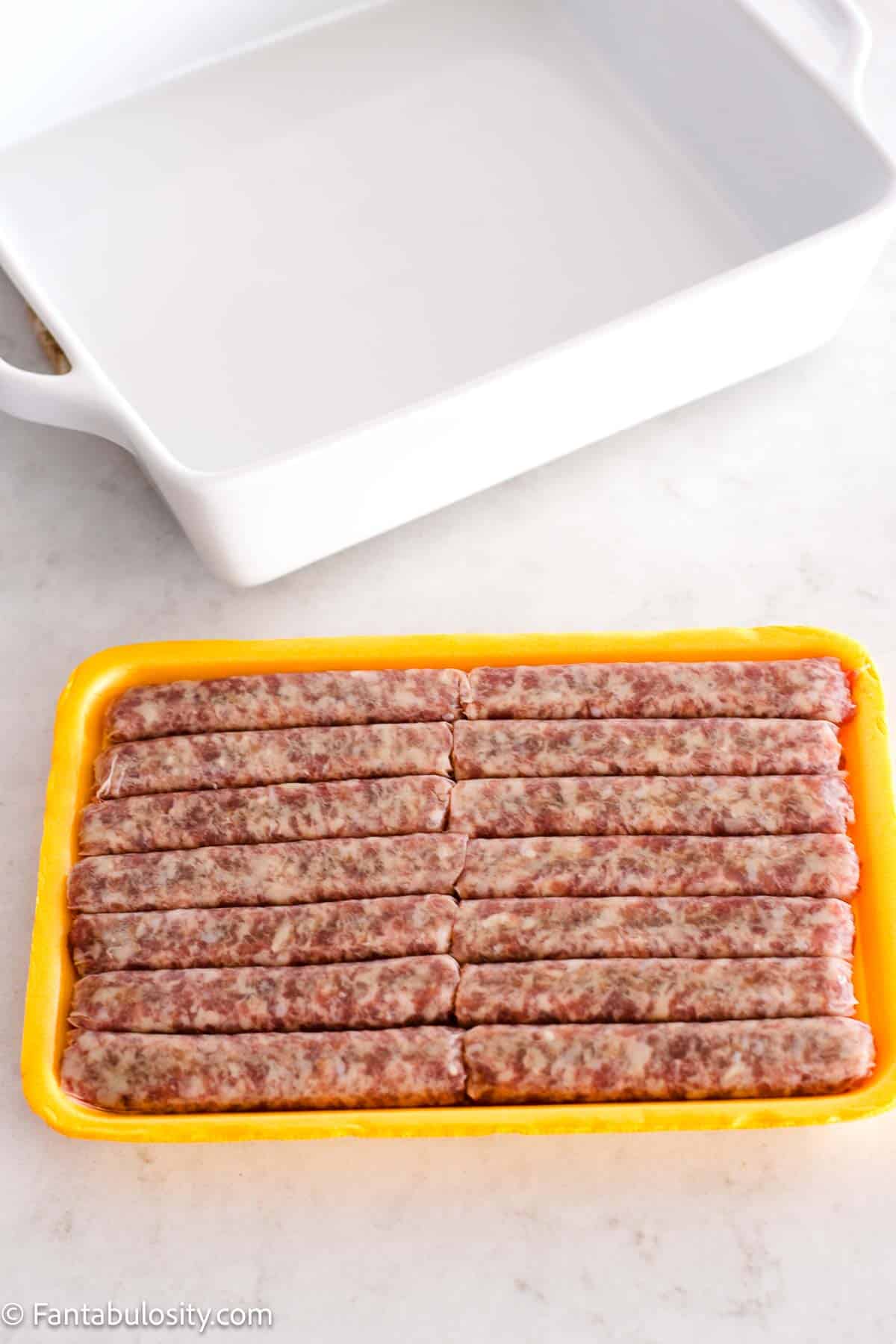 Raw, breakfast sausage links sitting on counter, next to baking dish.