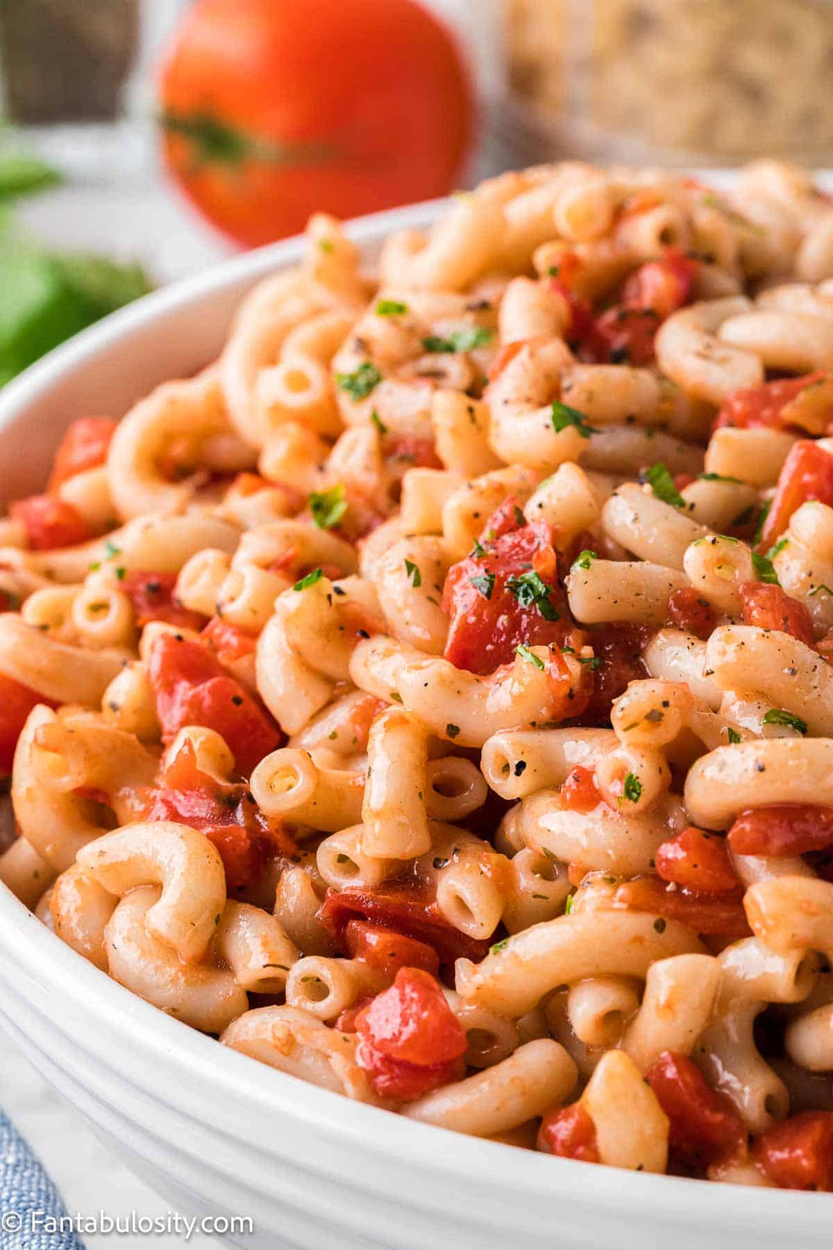 Macaroni and tomatoes in white bowl.