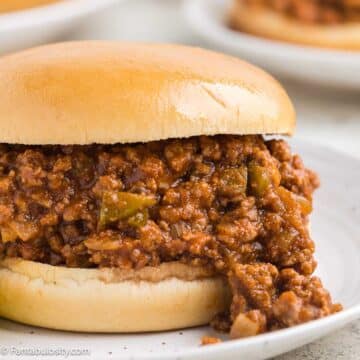 Old fashioned sloppy joes on a bun, sitting on a white plate.