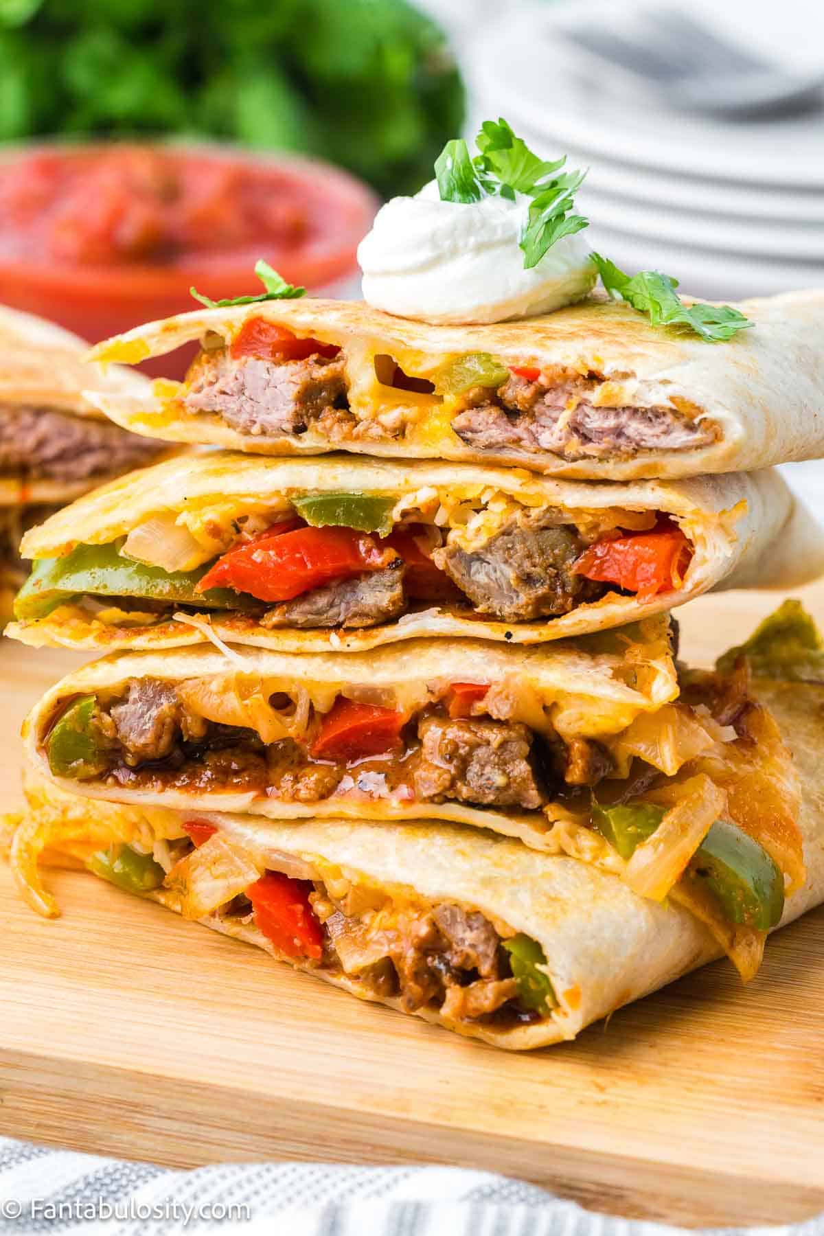 Steak quesadillas sliced and stacked and placed on cutting board.