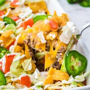 Walking Taco Casserole being lifted out of baking dish with spoon.