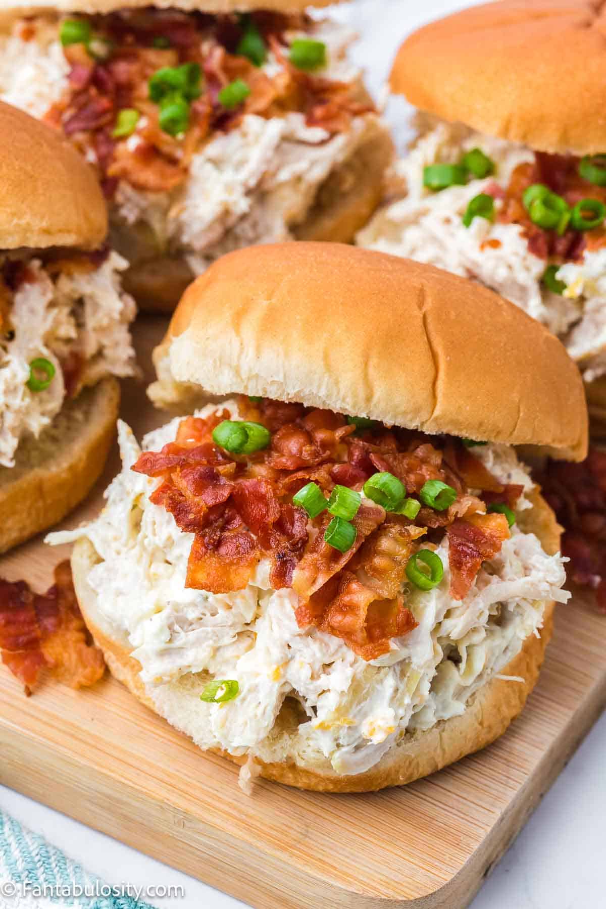 Chicken bacon ranch sandwiches on wooden cutting board.