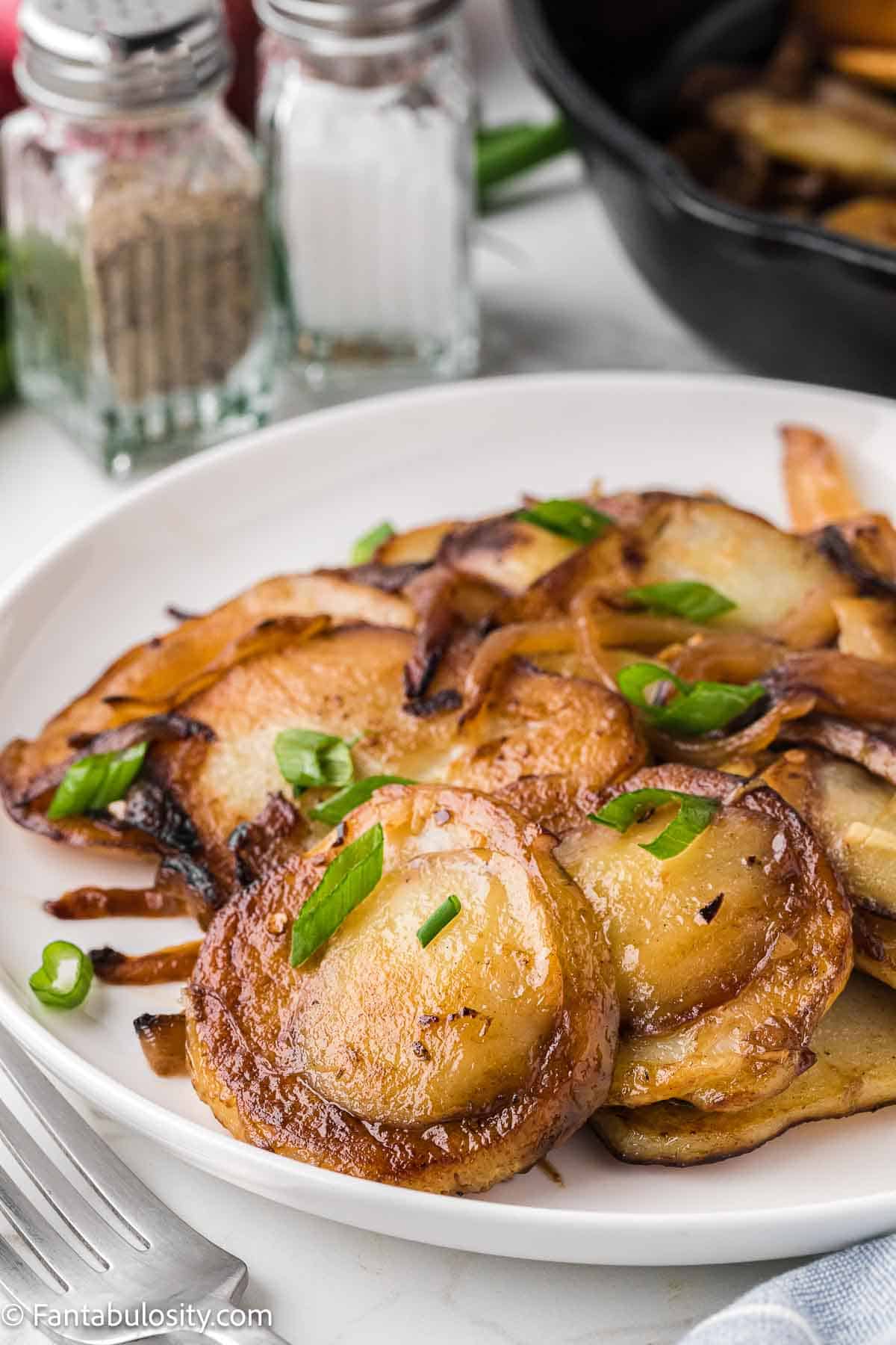 Cooked potatoes and onions on white plate.
