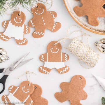Gingerbread ornaments on white table next to string and scissors.