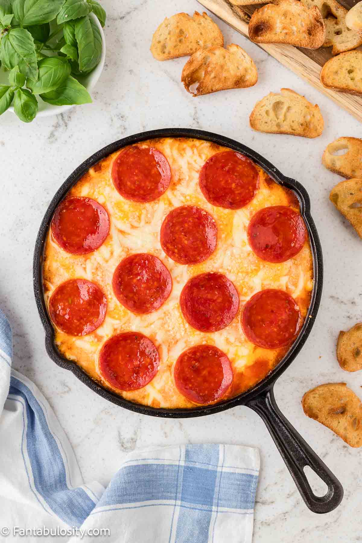 Baked pizza dip in a cast iron pan, sitting on counter.
