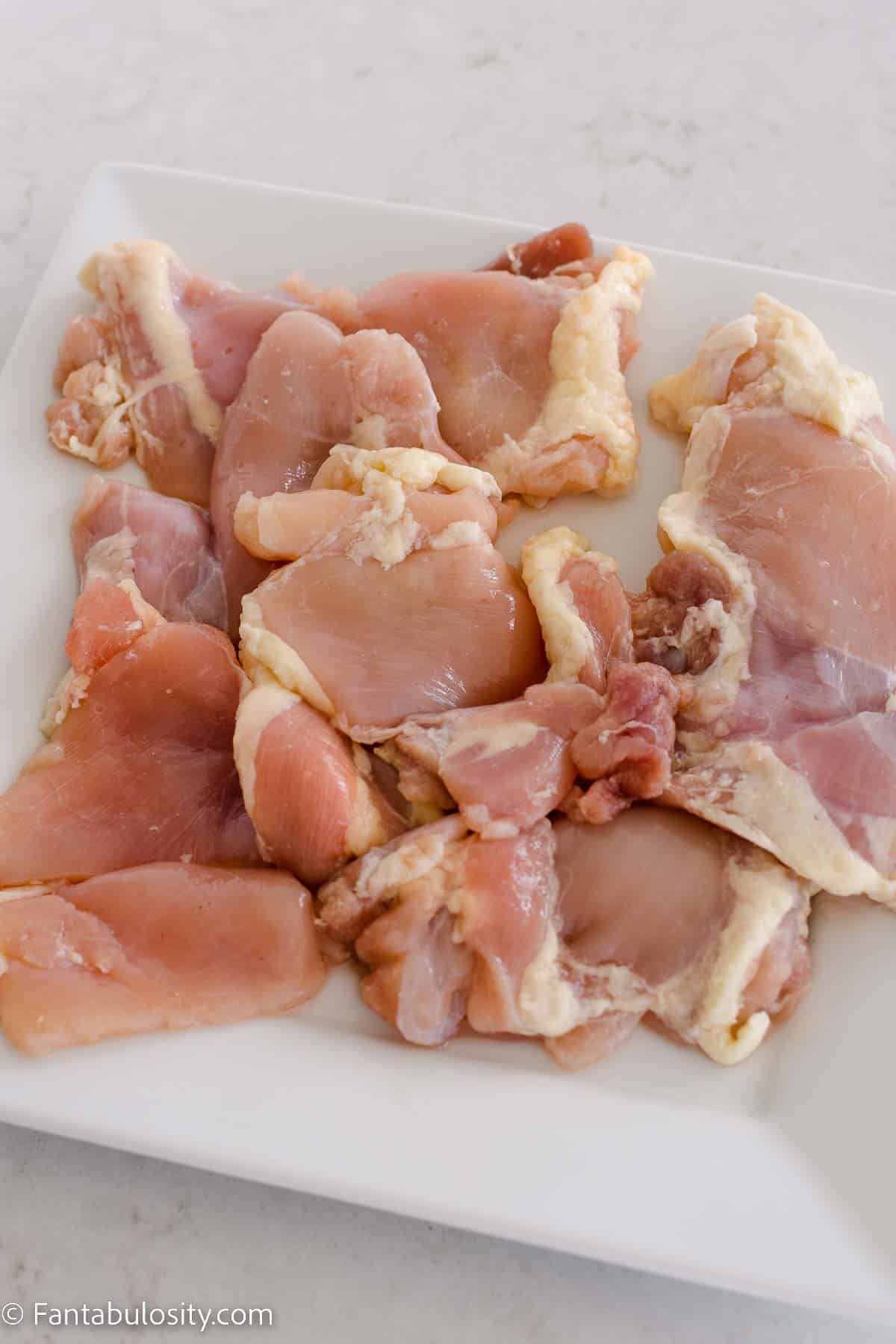 Boneless chicken thighs on white plate.