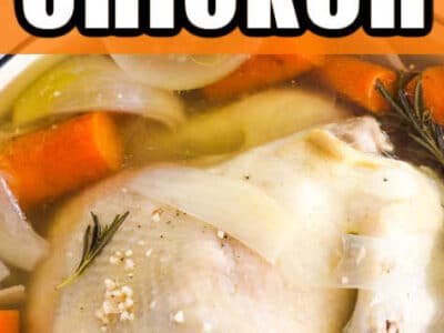 Close up of showing whole chicken in stock pot, with carrots, herbs and spices.