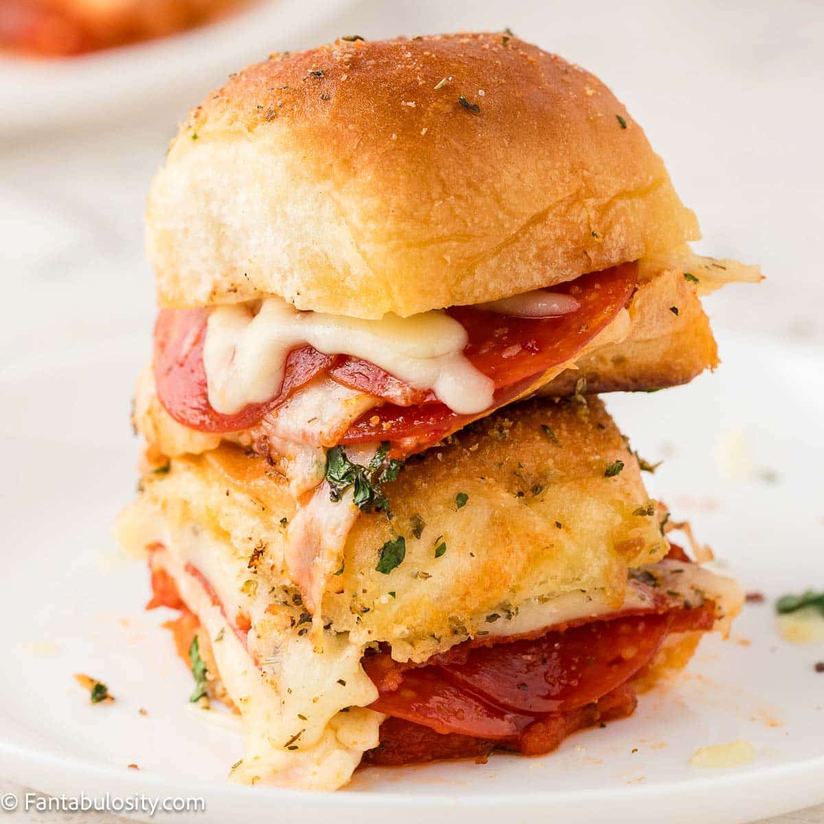 Close up of pizza sliders on white plate.