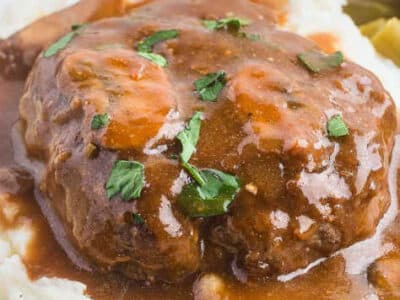 Salisbury steak sitting on a serving of mashed potatoes, topped with mushroom gravy.