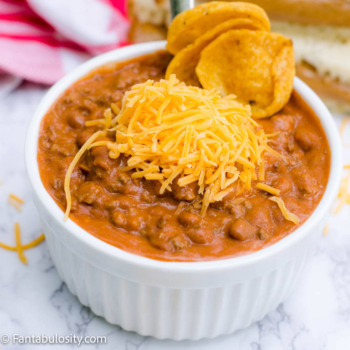 Homemade chili in small bowl with Fritos and cheese on top.
