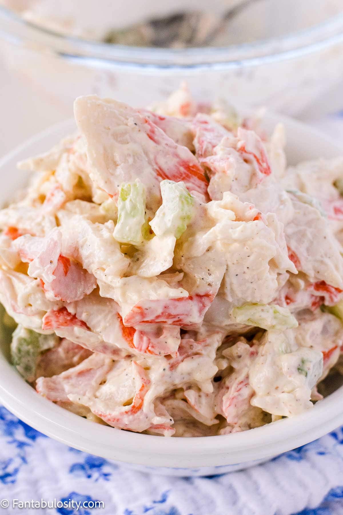 The best crab salad recipe in a bowl, next to bowl and spoon.