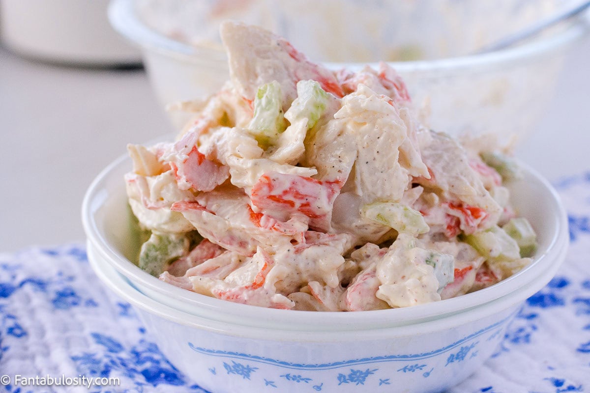 Crab salad in bowl, next to serving bowl.