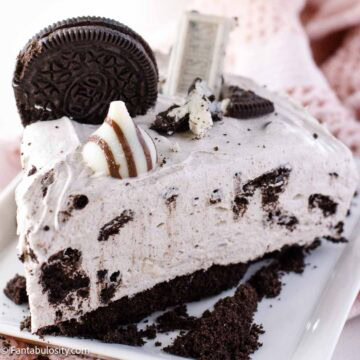 Slice of no bake Oreo cheesecake on a plate with a Hugs Kiss, candy bar and Oreo cookie.