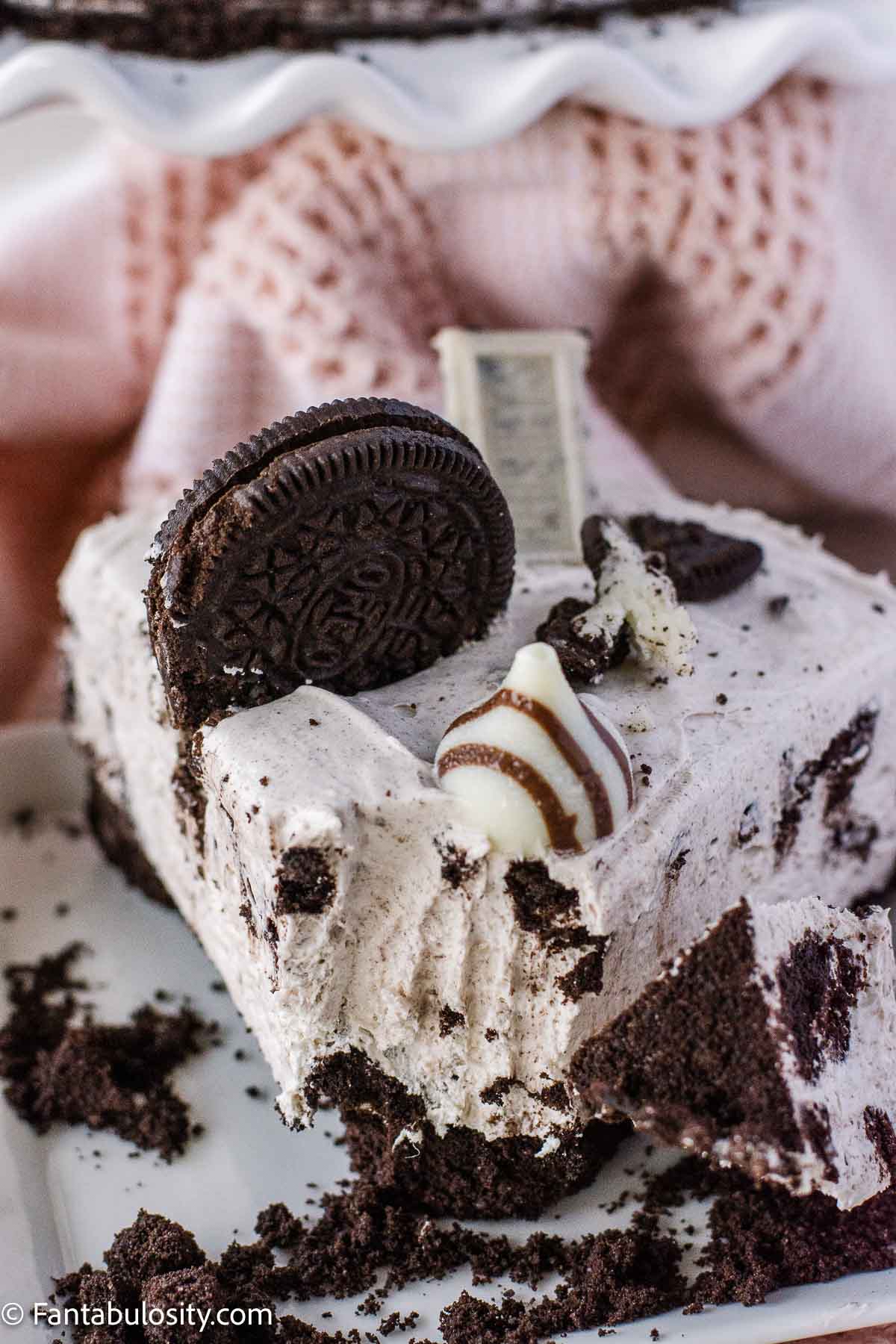 Slice of Oreo cheesecake with a bite taken off, sitting on a plate.