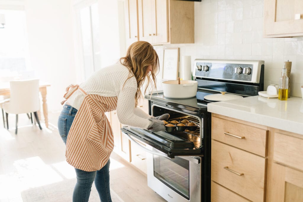 Jessica Burgess pulling muffins out of oven.