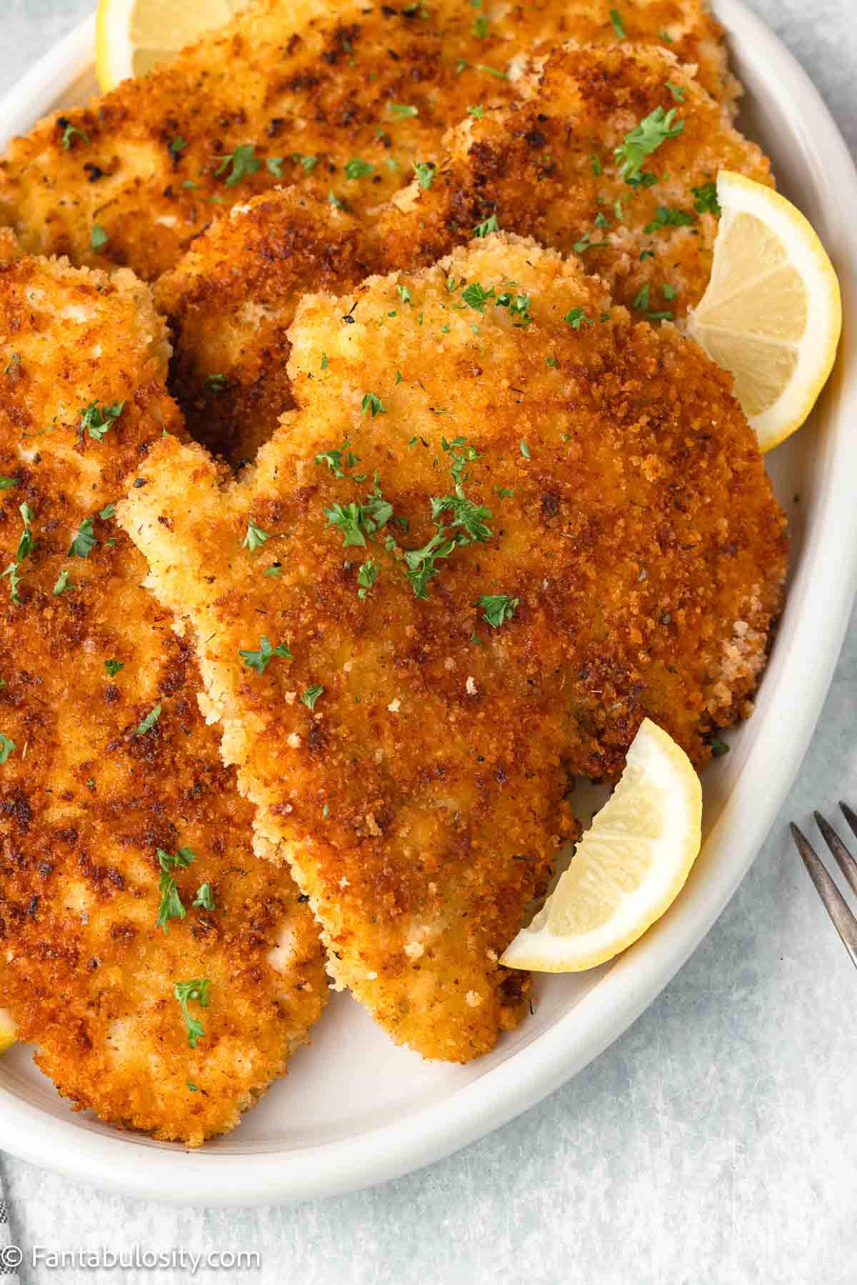 Panko Chicken breasts on plate with lemon slices.
