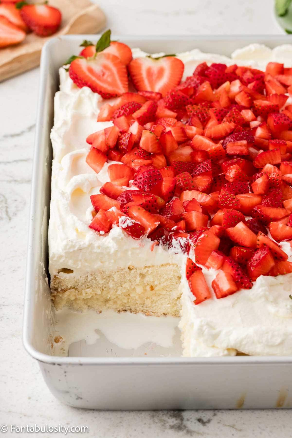 Slice of cake removed from pan of Strawberry Whipped Cream Cake.