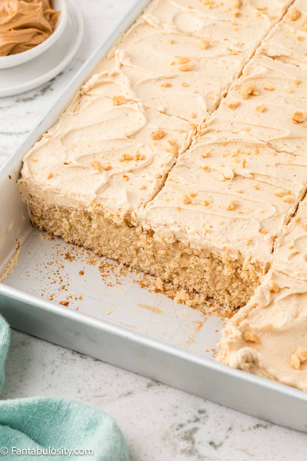 Peanut butter sheet cake in baking pan, with a couple of pieces removed.