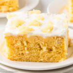 A slice of pineapple sunshine cake on a round plate.