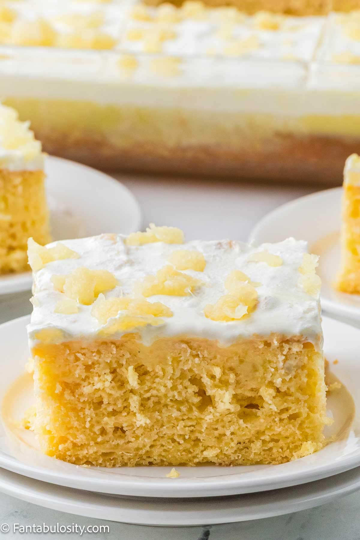 A slice of pineapple sunshine cake on a round plate.