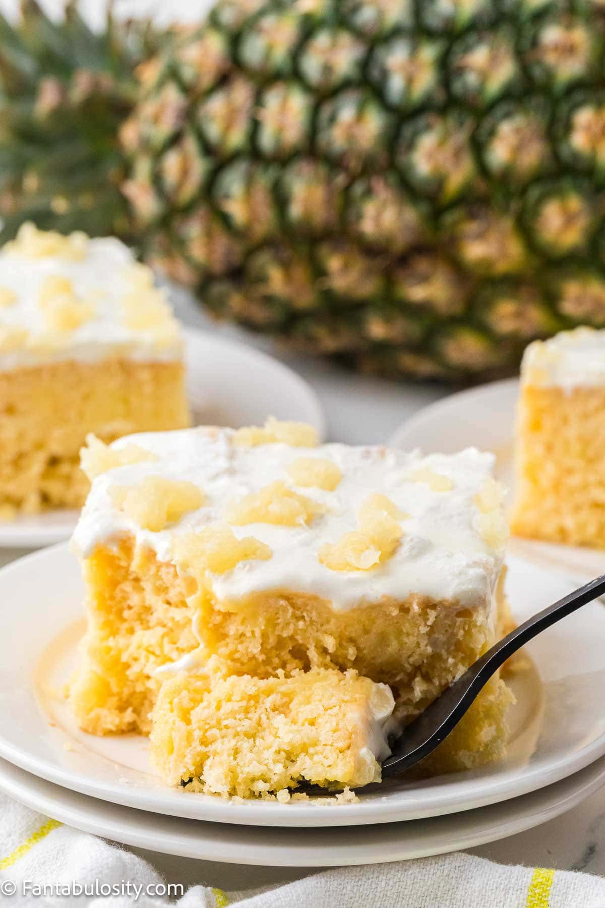 A slice of pineapple sunshine cake, with a fork taking a bite off.