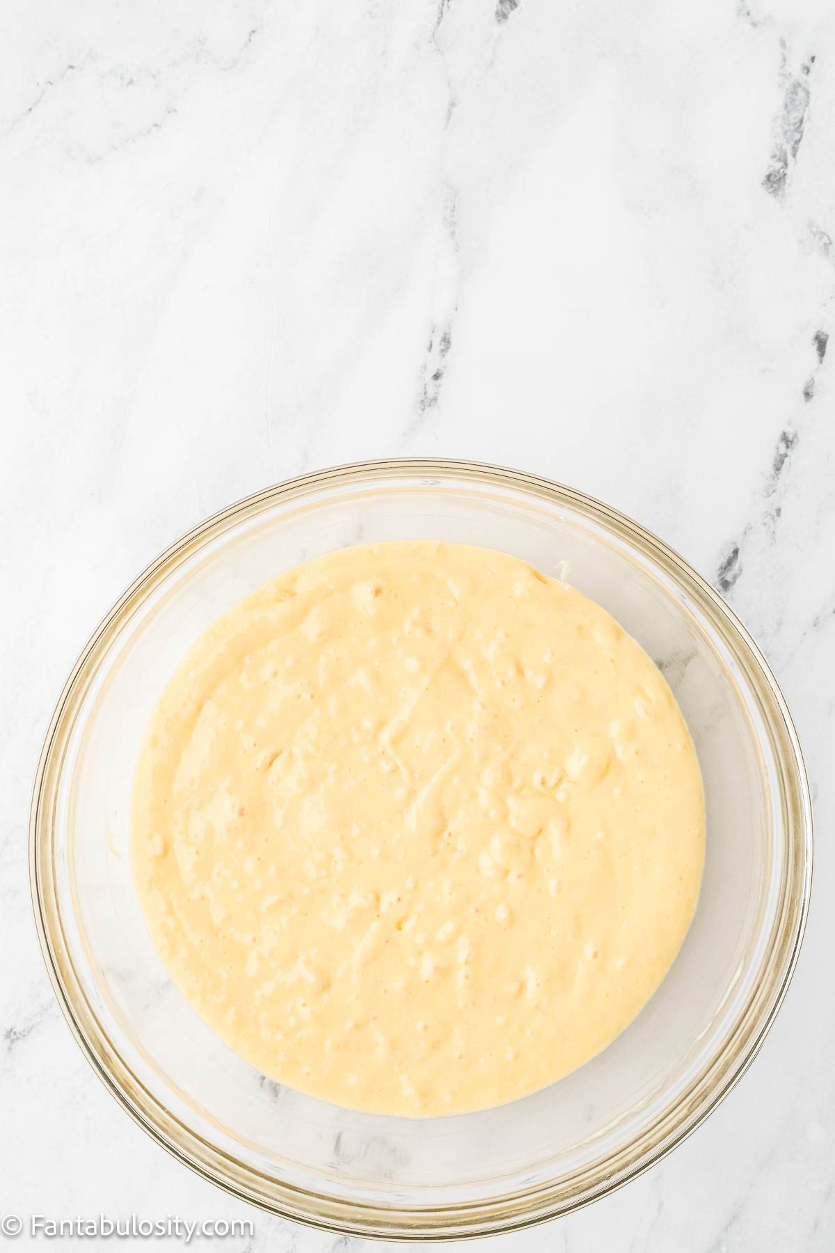 Cake batter of cake mix, oil, juice and more in mixing bowl.