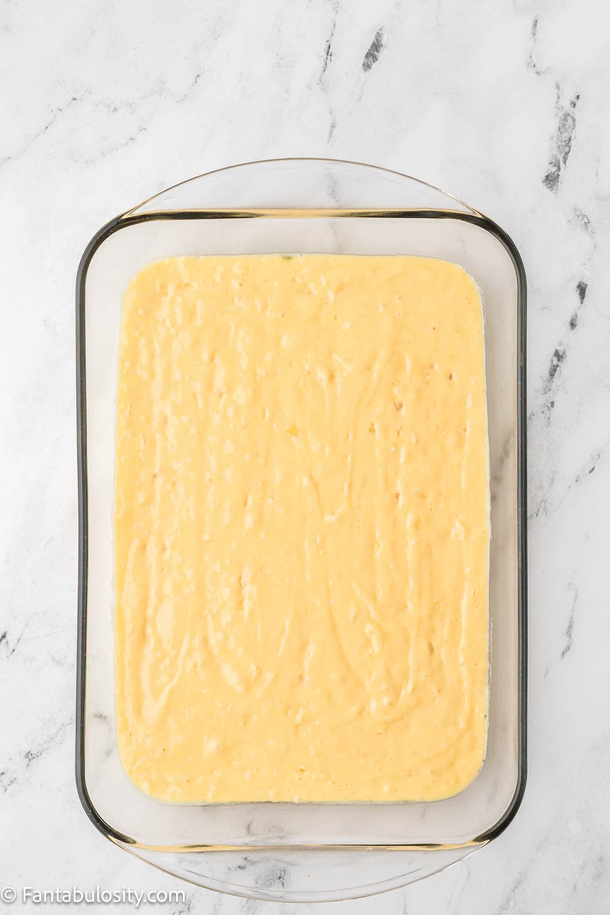 Pineapple sunshine cake poured in to baking dish.