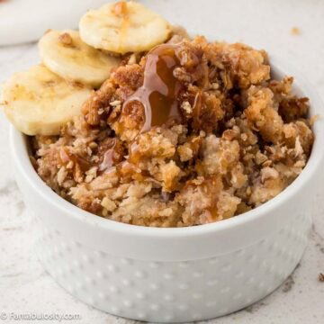A serving of banana dump cake in a small ramekin with caramel sauce and sliced bananas.