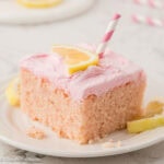 Slice of pink lemonade cake, with pink and white striped straw sticking out the top.