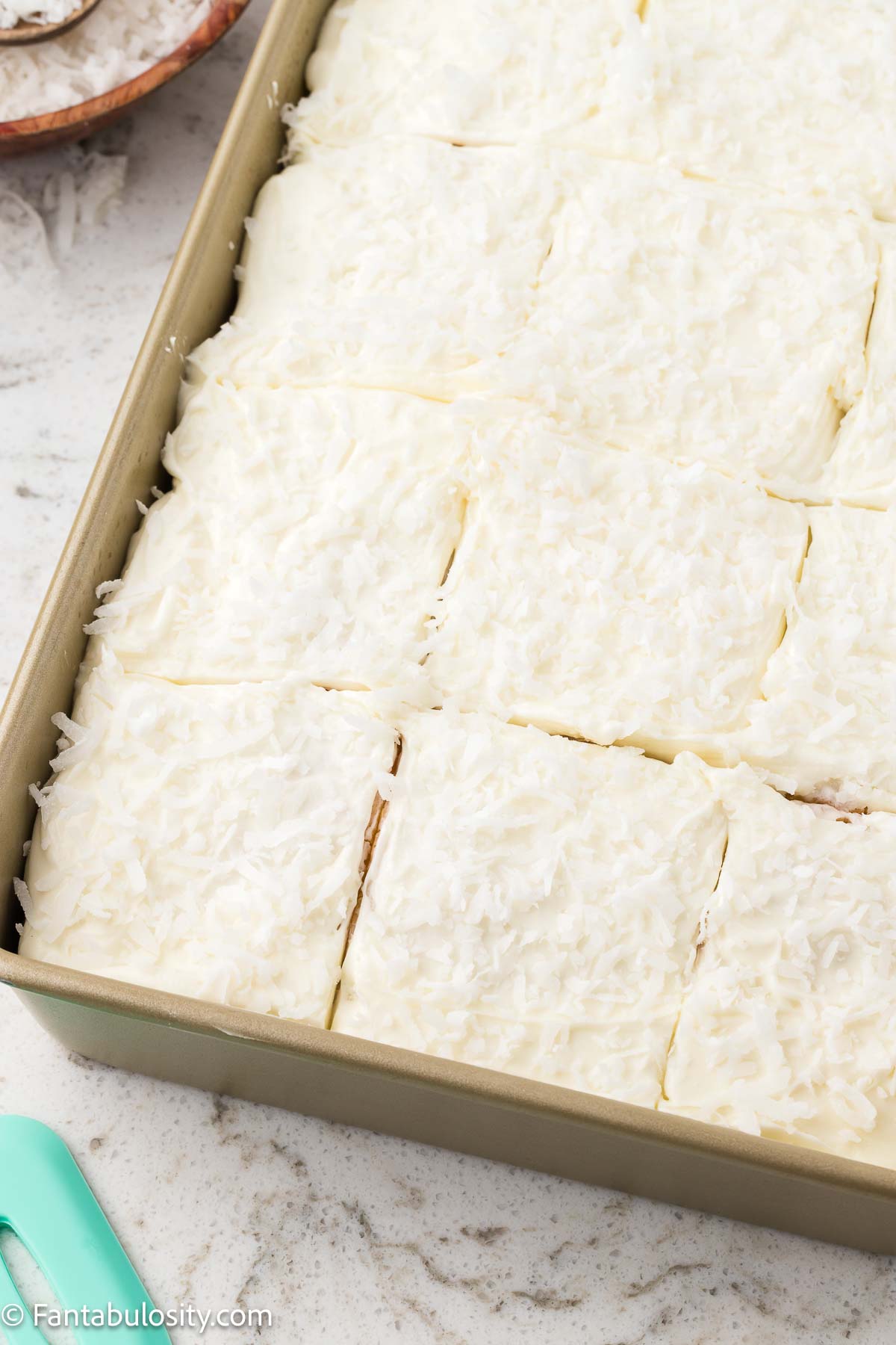 Coconut sheet cake with coconut frosting in baking pan.