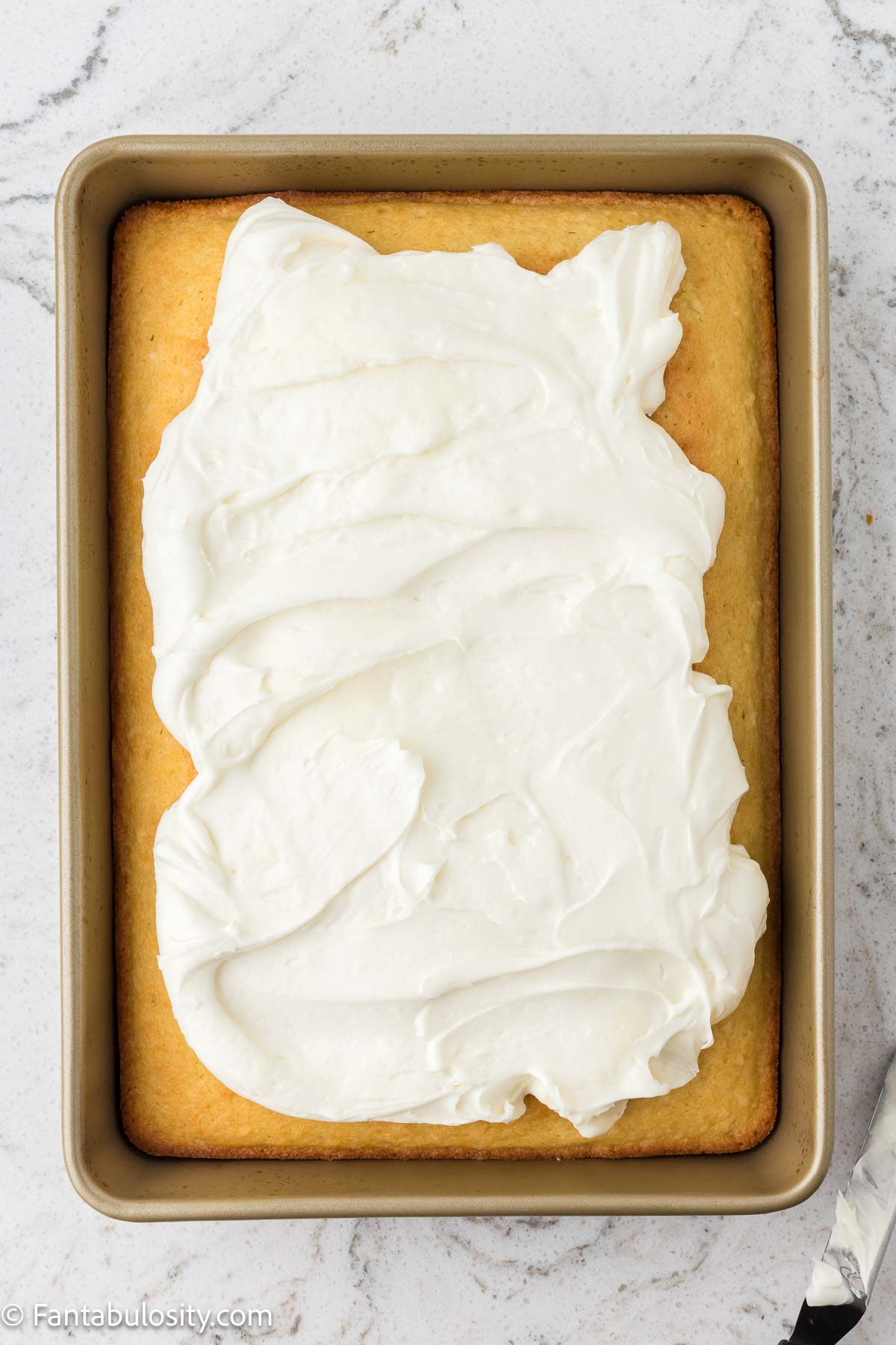 Baked coconut cake with coconut frosting spread on top.