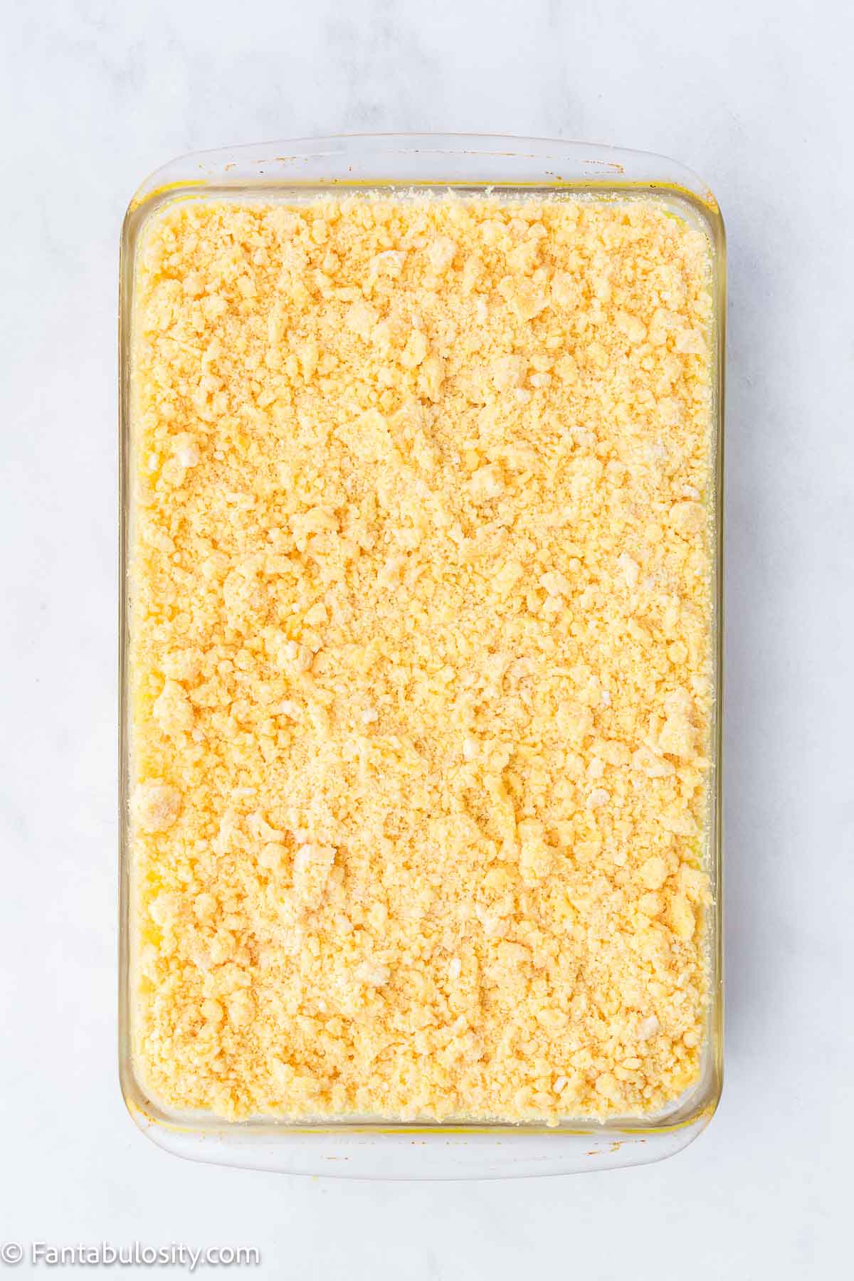 Cake mix and butter mixture spread on the top of the lemon dump cake.