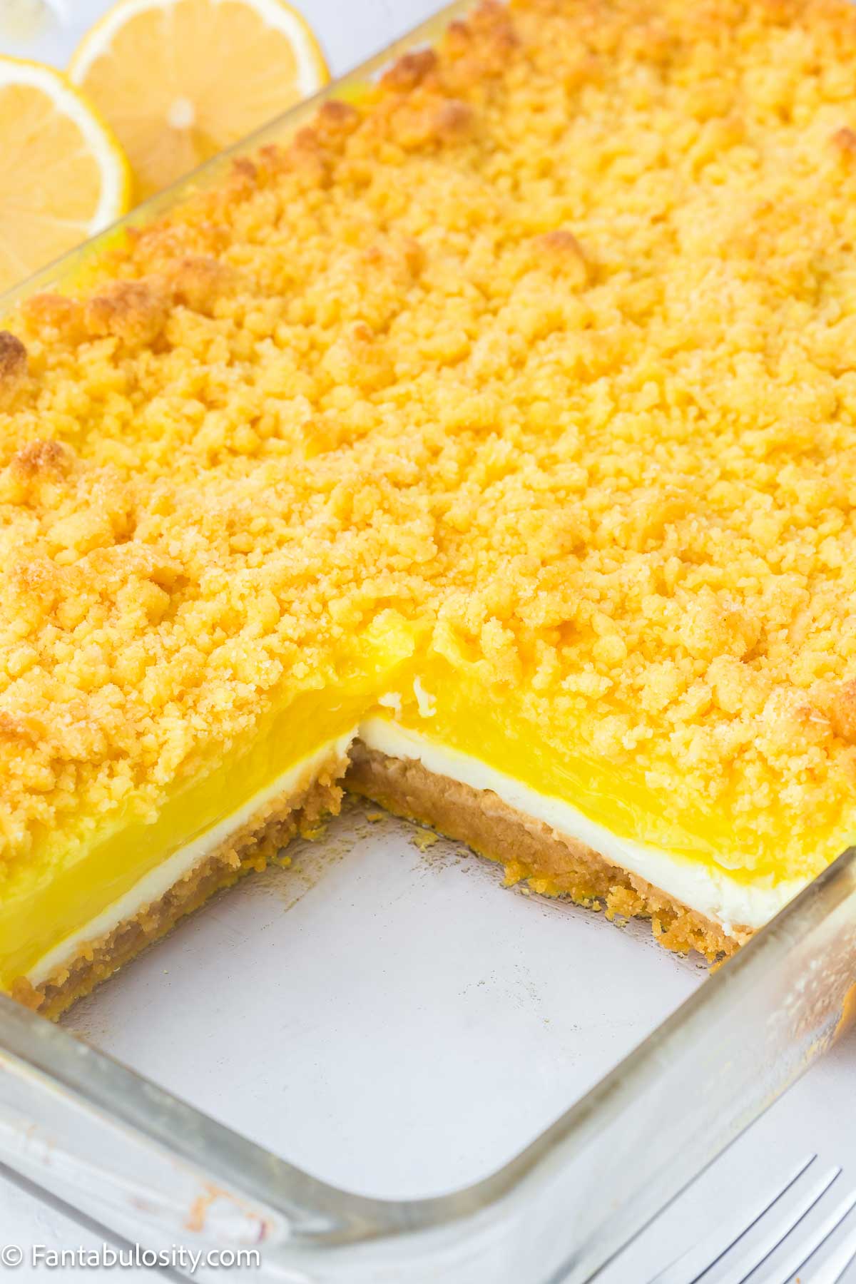 Serving removed from lemon dump cake in baking dish, showing layers.