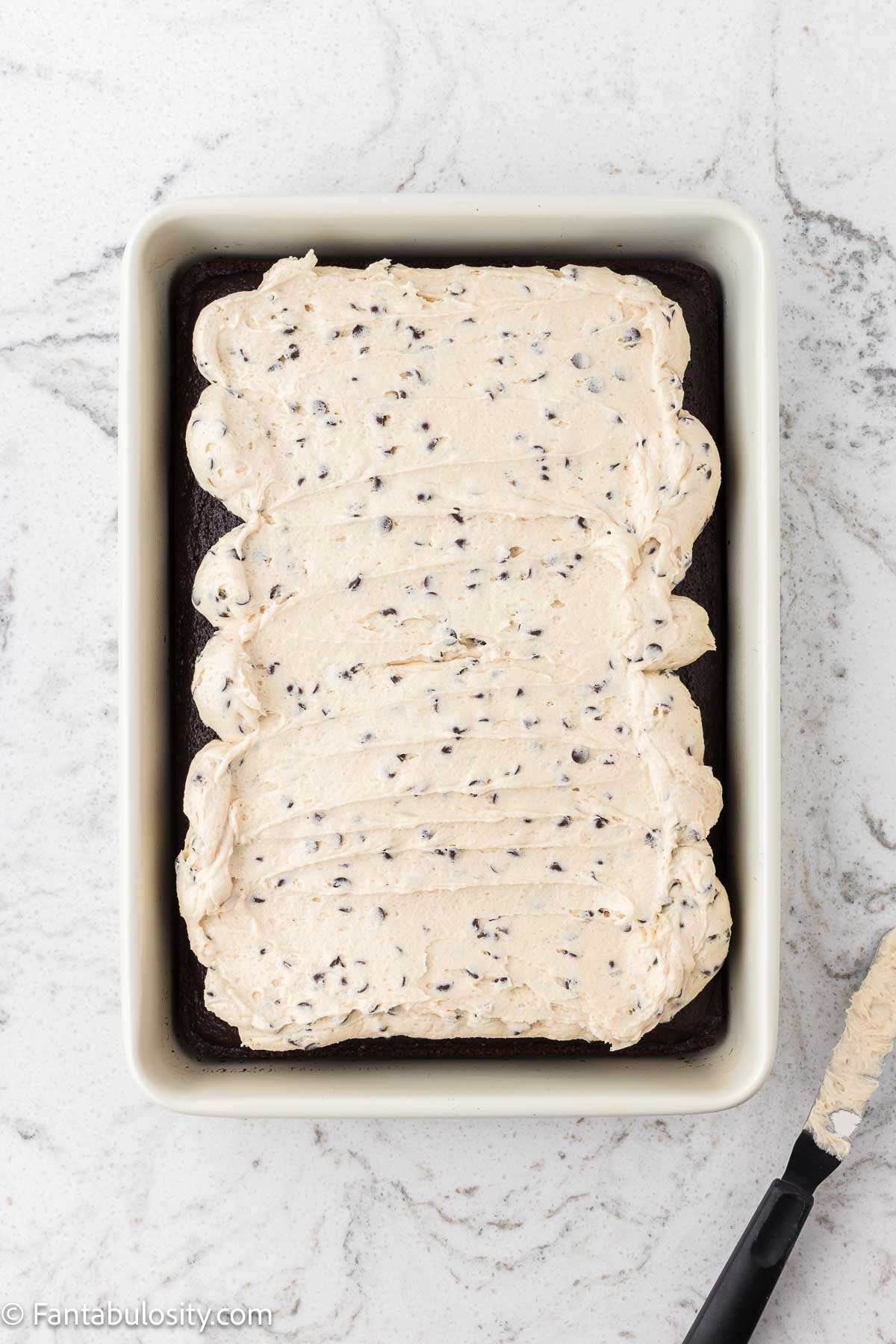 Cookie dough frosting spread on top of chocolate sheet cake.