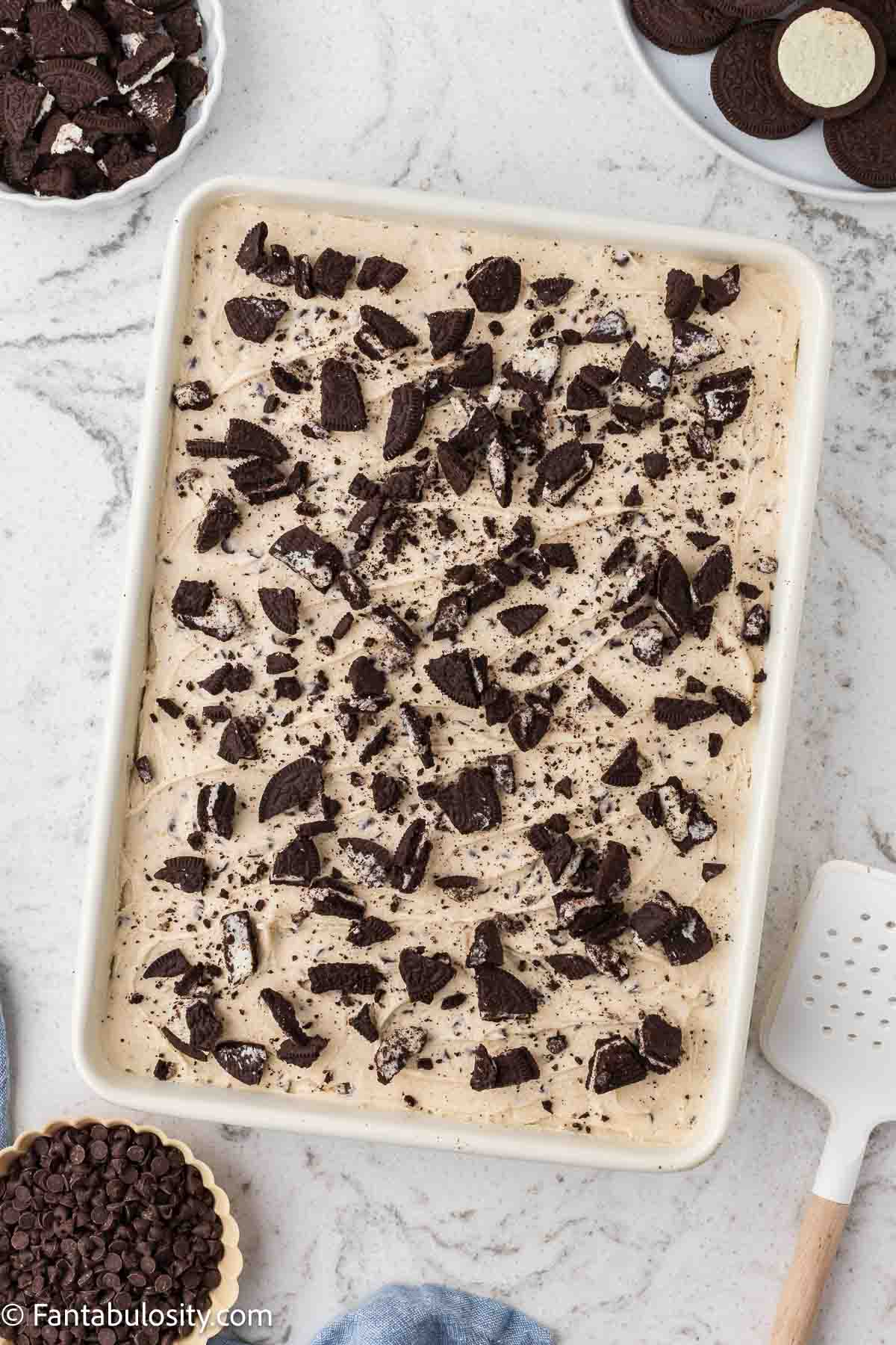 Crushed Oreos on top of cookie dough frosting and chocolate cake.