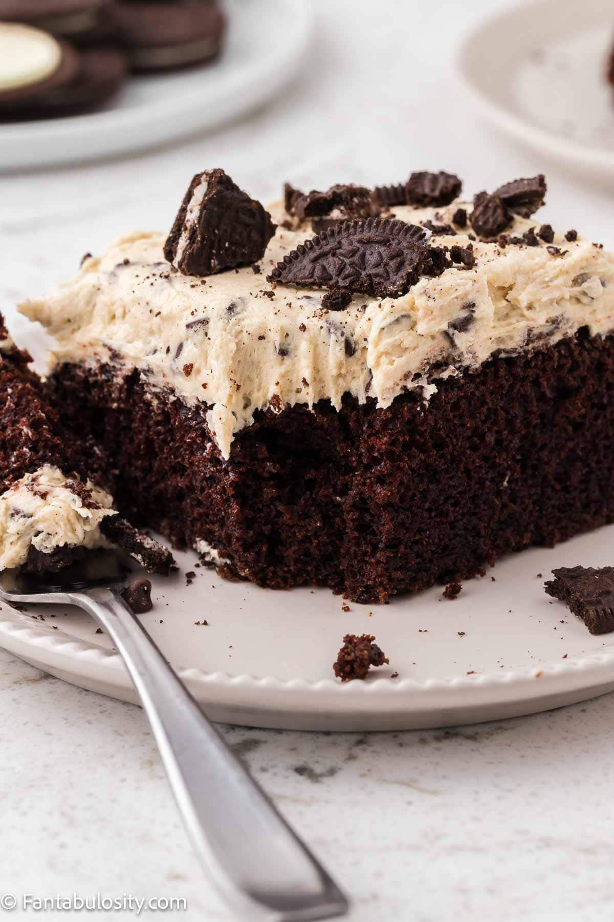 Slice of chocolate sheet cake that's topped with cookie dough frosting and Oreos.