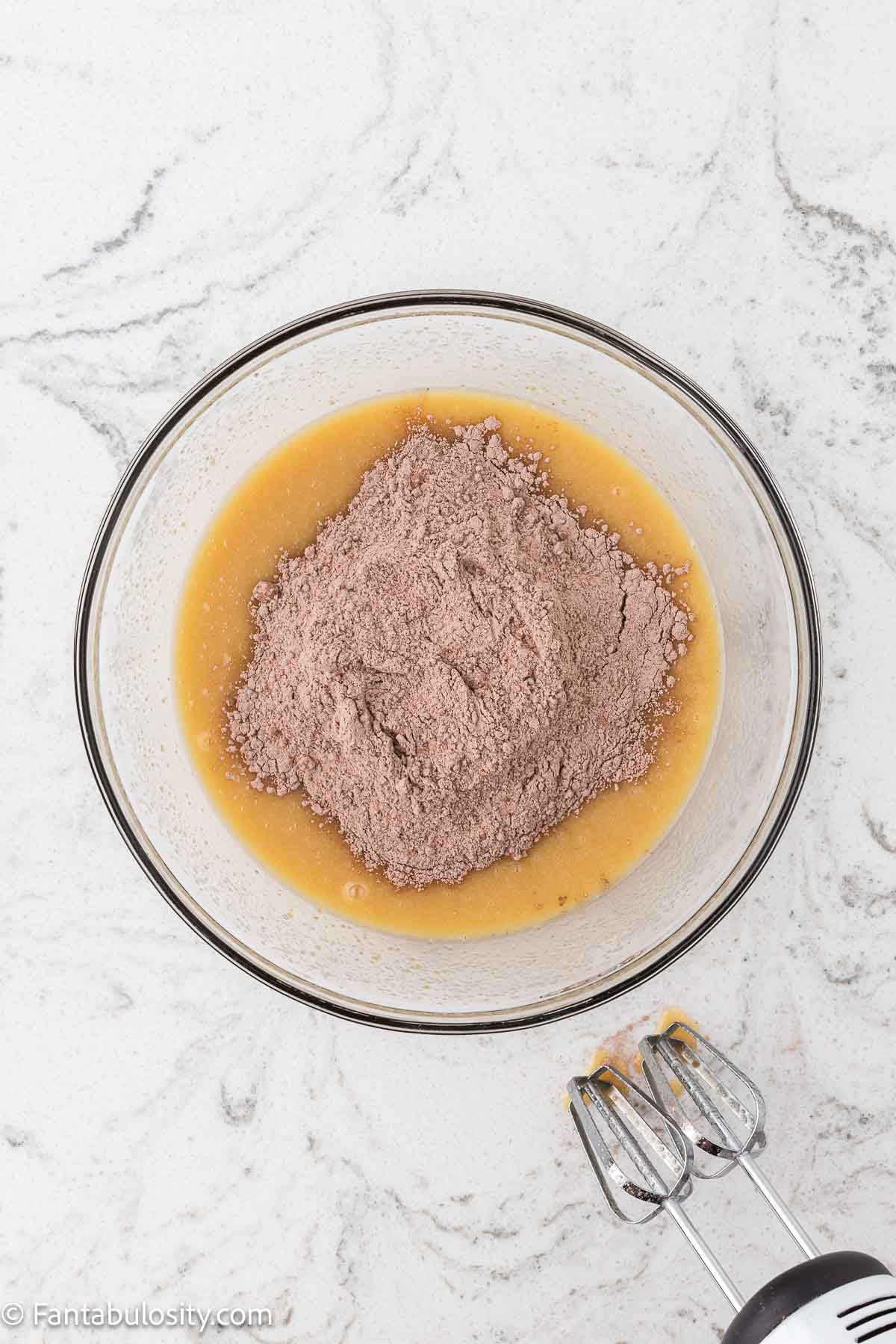Dry ingredients being added to wet ingredients in mixing bowl.