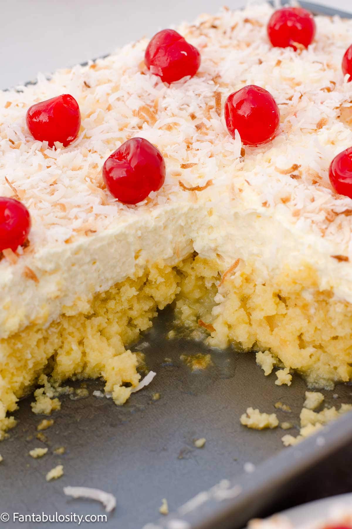 Pina colada cake in a baking pan, with slices cut out of it.