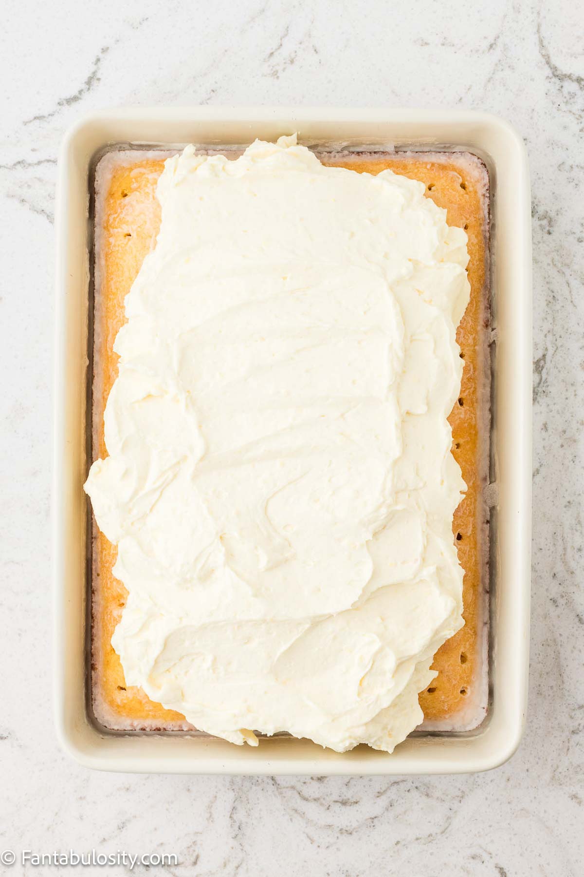 Frosting spread on top of baked pina colada cake.