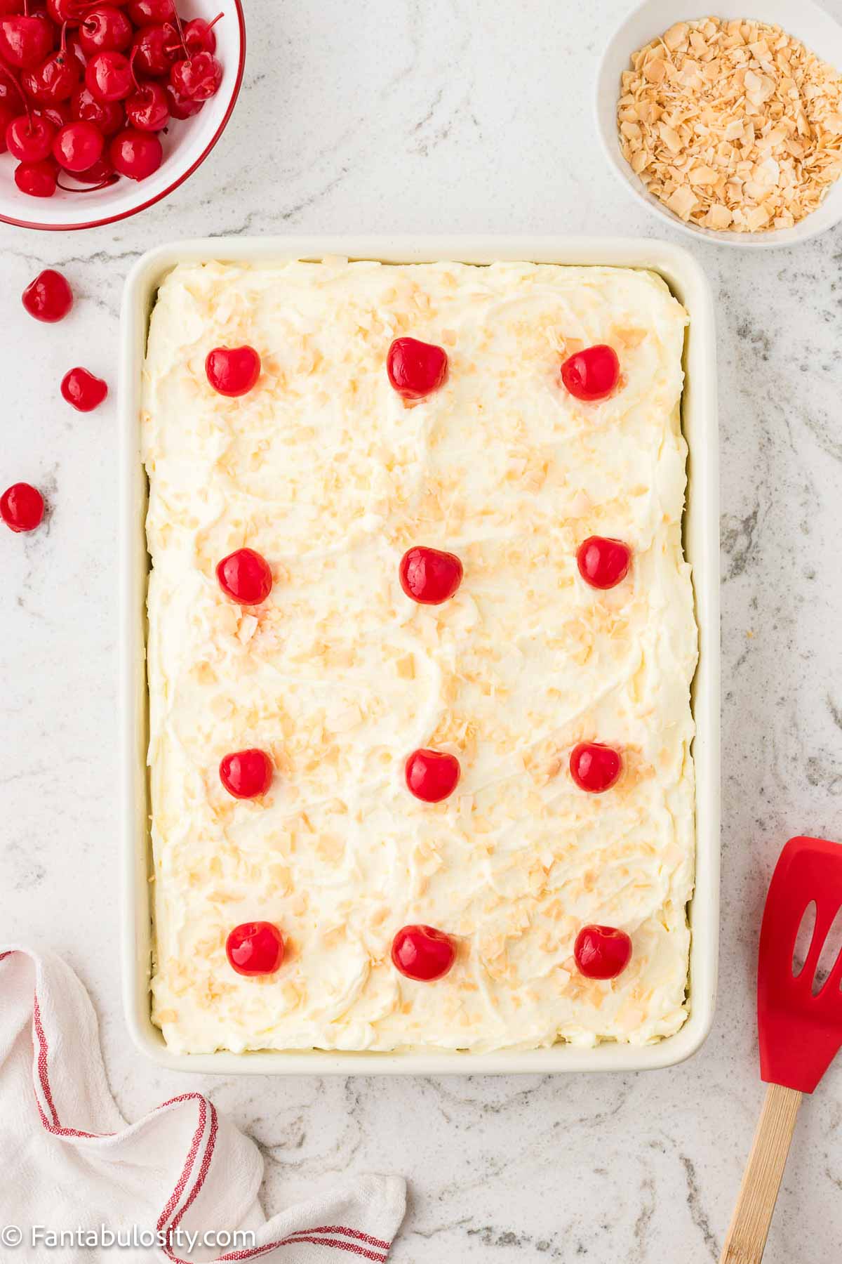 Frosted pina colada cake, topped with cherries.