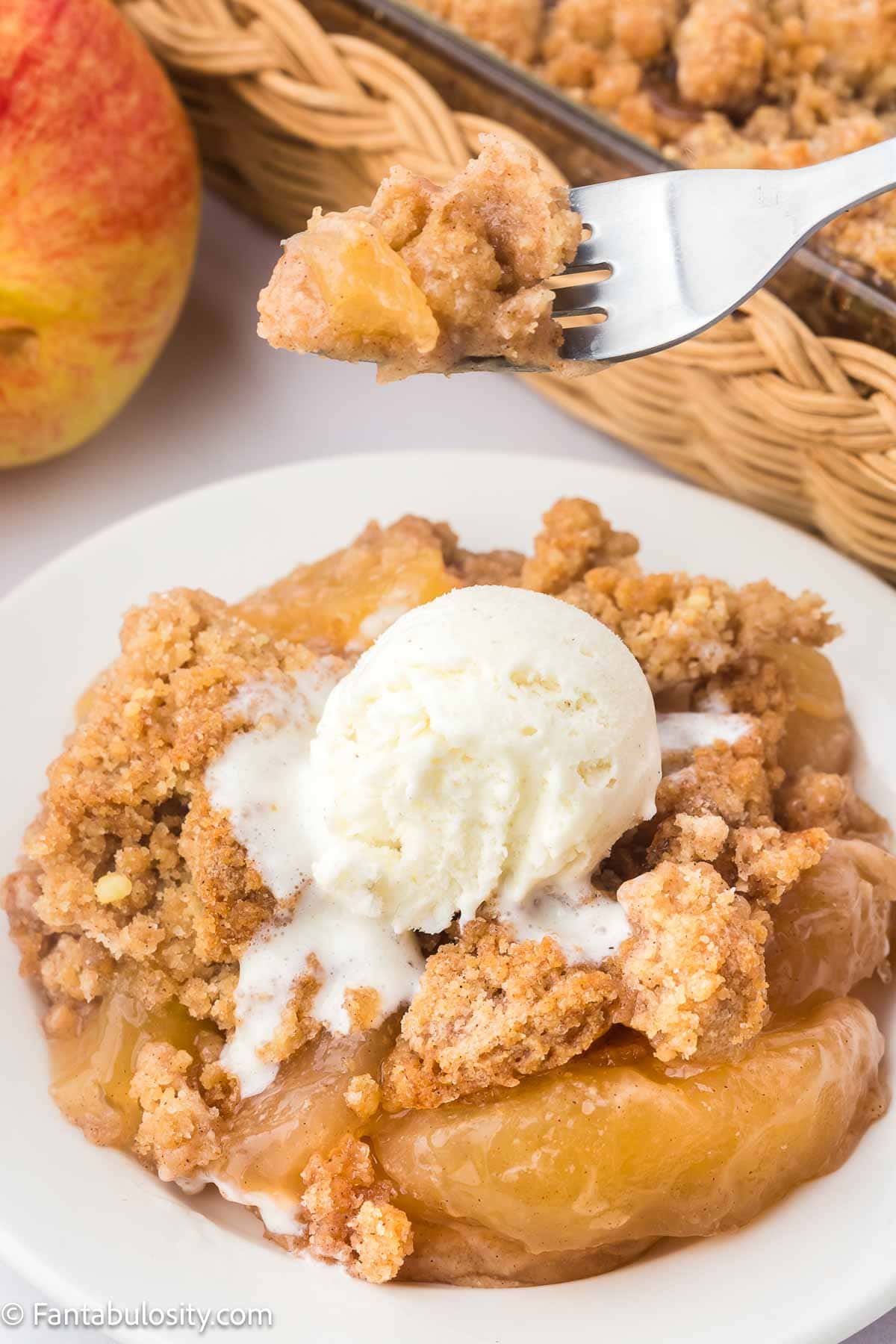 Serving of apple snickerdoodle dump cake on a round plate, with vanilla ice cream.