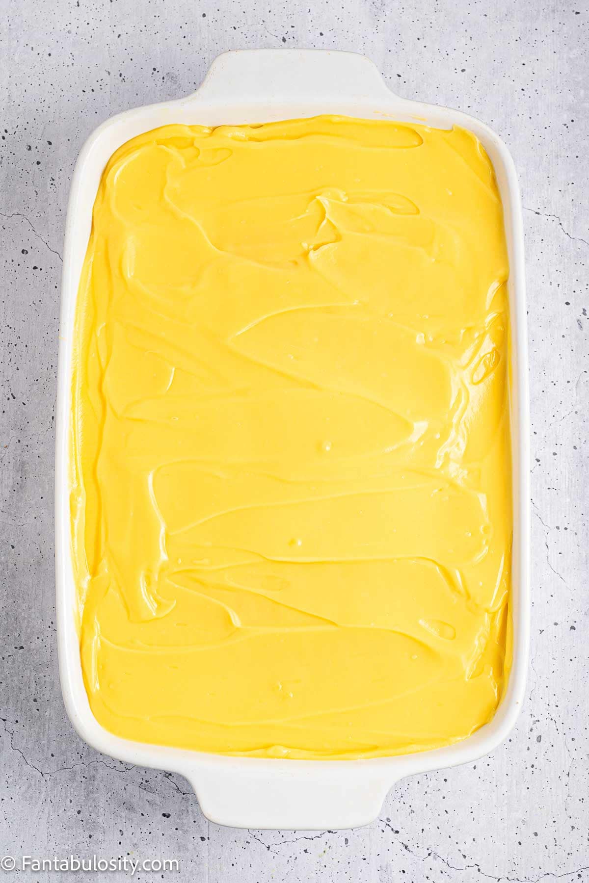 Vanilla pudding mix poured on top of baked cake.