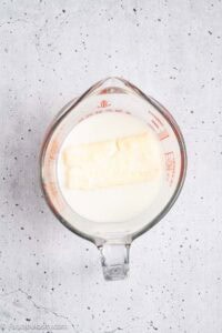Milk and butter in measuring cup for heating.