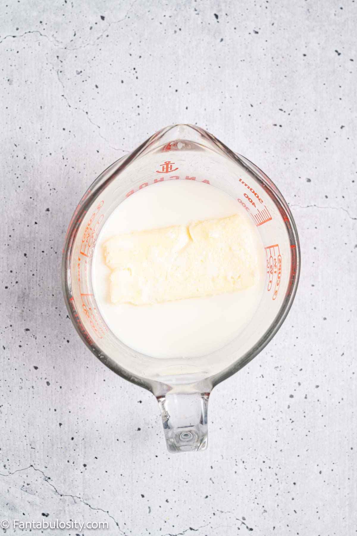 Milk and butter in measuring cup for heating.