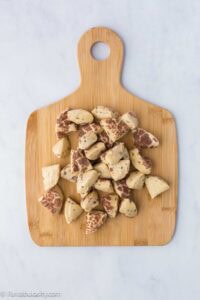 Cinnamon rolls cut up in to pieces, and sitting on a cutting board.